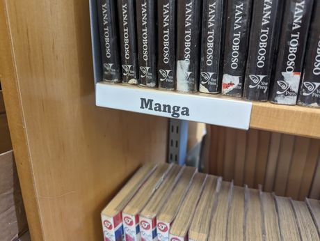 The old Library signage - it is a white slip of paper, with manga written on it in black text.